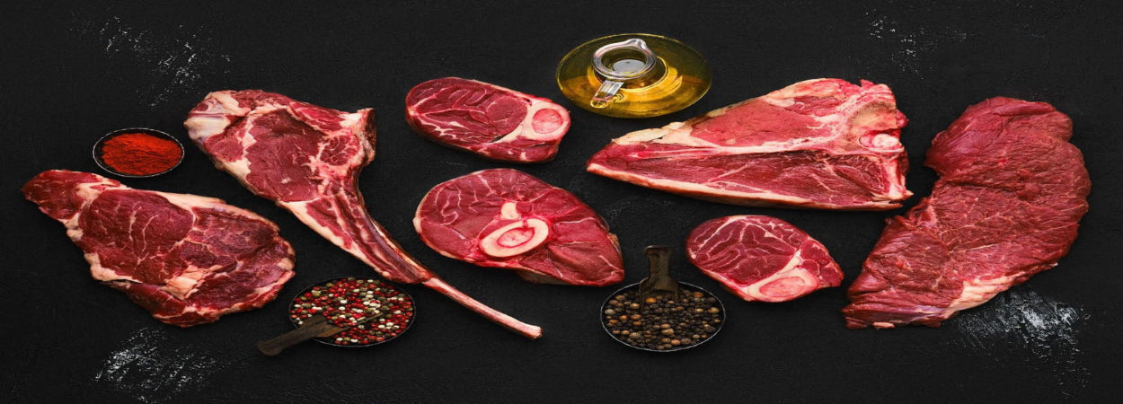 Assorted raw red meats with spices on a dark surface